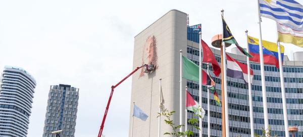 Street artist Fintan Magee high atop a cherry picker creating the mural at the Vienna International Centre. Street artist Fintan Magee high atop a cherry picker creating the mural at the Vienna International Centre.